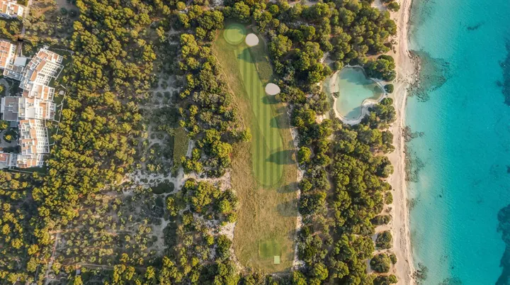 Akyar Coast from the air: a fairway through umbrella pines beside a white beach and a turquoise sea.