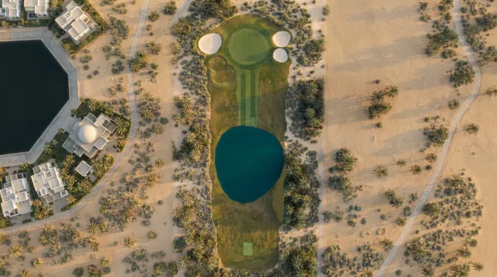 Al Qasira from the air: a fairway with a blue pond in front of the green, in pale sand beside white villas.