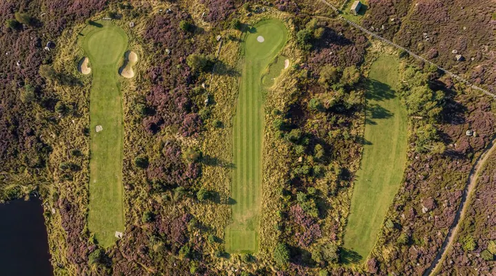 Holbeck Moor from the air: three fairways through purple heather and birch, with a dark tarn in the corner.